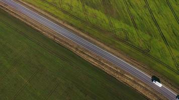 Top view of a cars driving along a rural road between two fields video