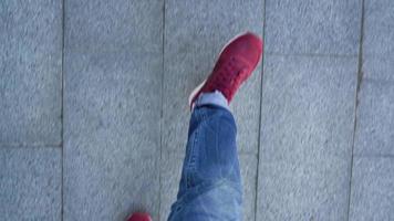 Top view of men's legs in red sneakers walking on asphalt video