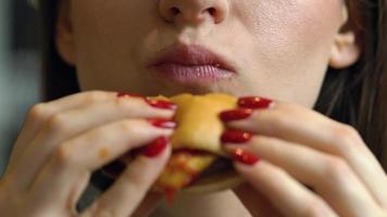 Woman eats a hamburger in a cafe video
