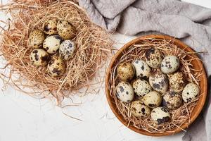 top view quail eggs in wooden bowl and nest on white table background photo