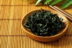 dried Laminaria Kelp Seaweed on wooden plate Background. dried Laminaria or kelp Seaweed on wooden plate Background. konbu, alga, wakame photo