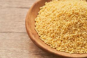 pile of sorghum or sorghum grain, millet grain or millet seed in wood plate on wooden table background photo