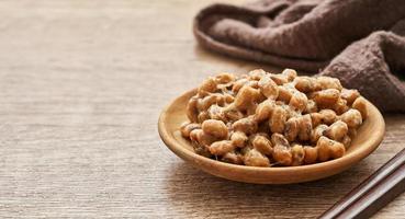 Natto or Fermented Soybean in wood plate and chopsticks on wooden table background. Natto or Fermented Soybean Japanese food photo