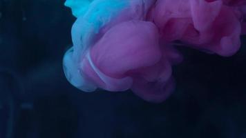 Color drop underwater creating a silk drapery. Ink swirling underwater. Slow motion video