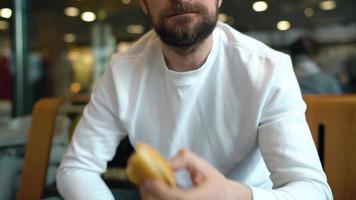 Man eats a hamburger in a cafe video