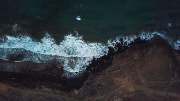 Haut vue de une déserté côte. rocheux rive de le île de tenerife. aérien drone métrage de mer vagues atteindre rive video