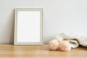 Blank picture frame mockup on white wall and pink flowers. View of modern style interior with artwork mock up on wall. Home staging and minimalism background photo