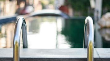 Closeup of pool steps or ladder at the swimming pool in the soft-focus background photo