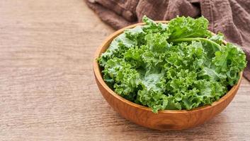 fresh green Kale leaves bunch leaf cabbage in wood plate isolated on white background. green kale or leaf cabbage in a wooden bowl isolated photo