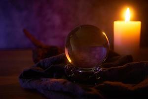 concept of fortune-telling wooden table and white candle with a crystal ball and tarot cards on dark background with copy space photo