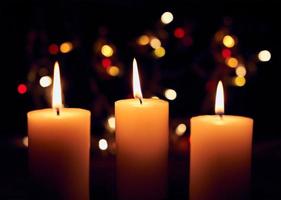 Flame candles with decorative lights on black table background photo