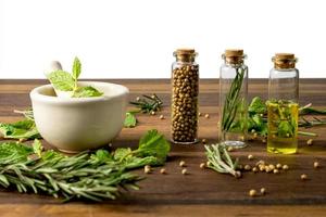green herbs in mortar with essential oil on wooden table photo
