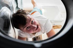 Man view from washing machine inside. Male does laundry daily routine. photo