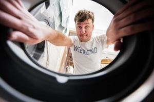 Man view from washing machine inside. Male does laundry daily routine. photo