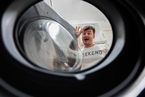 Man view from washing machine inside. Male does laundry daily routine. Bye bye. photo