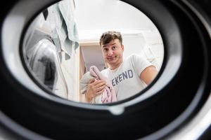 Man view from washing machine inside. Male does laundry daily routine. photo