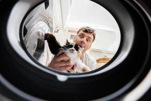 Man with cat view from washing machine inside. Male does laundry daily routine. photo