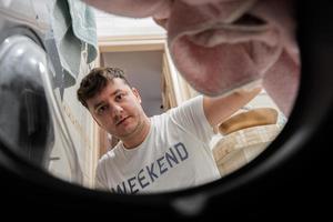 Man view from washing machine inside. Male does laundry daily routine. photo