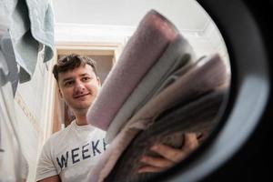 Man view from washing machine inside. Male does laundry daily routine. photo
