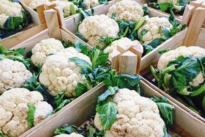 Fresh cauliflowers in wooden boxes sold in supermarket photo