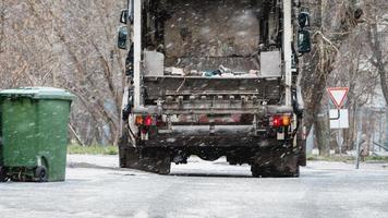 Garbage truck, dustcart with bin lift, household waste removal in residential area in winter, refuse container, snow photo