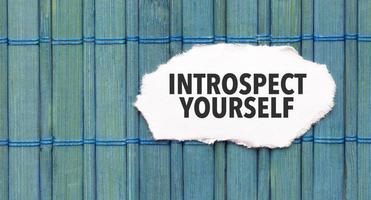 Text introspect yourself on the piece of paper on the green wood background photo