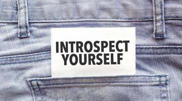 Text introspect yourself on a white paper stuck out from jeans pocket. Business concept photo