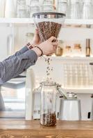 A barista pours coffee beans photo