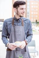A smiling barista holding coffee photo