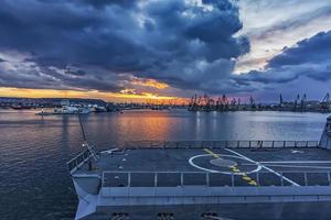 parte de el fragata, un helicóptero aterrizaje a puesta de sol en el puerto. militar barco. marina efectivo foto