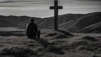 Man in front of a wooden cross in the countryside. Black and white. artwork photo