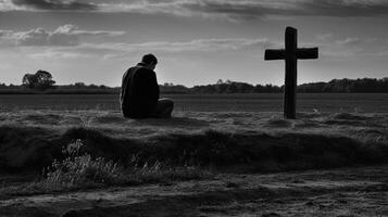 Man in front of a wooden cross in the countryside. Black and white. artwork photo