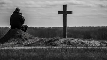 Man in front of a wooden cross in the countryside. Black and white. artwork photo