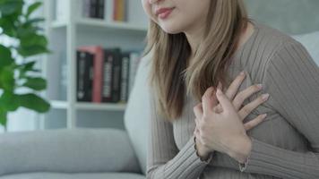 Herz Attacke, Hand halten Truhe mit Herz Attacke Symptome, asiatisch Frau haben Truhe Schmerzen verursacht durch Herz Krankheit, Herz Leck, Koronar Herz Krankheit, drücken auf das Truhe mit ein schmerzlich Ausdruck. video
