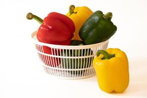 Sweet bell peppers in the white basket with water drops isolated on white background. photo