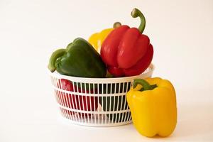 Sweet bell peppers in the white basket with water drops isolated on white background. photo