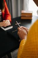 dos personas leyendo y estudiando la biblia en casa y rezando juntas. estudiando la palabra de dios con amigos. foto