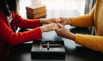 dos personas leyendo y estudiando la biblia en casa y rezando juntas. estudiando la palabra de dios con amigos. foto