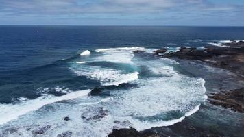 stark Wellen Absturz gegenüber das felsig Küste auf ein windig Nachmittag video