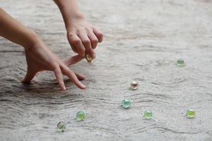 Closeup kid hands play marble glassballs. Concept, traditional childen play toy. Recreation activity to make concentrate for kids, fun and competition games photo