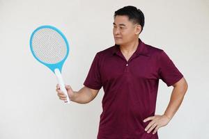 Asian man holds  mosquito electric swatter racket. Concept, Technology electric device to kill mosquitoes, insects, bugs by swatting to flying insects that can cause disease or annoyed feeling. photo