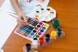 Closeup student is studying art subject, painting, art activity, enjoy and concentrate on favorite activity with many colors. Concept, Education. Learning by doing, enhance kid's imagination. photo