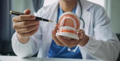 los dentistas están discutiendo problemas dentales al informar la imagen de rayos X en la pantalla del portátil a los pacientes. foto