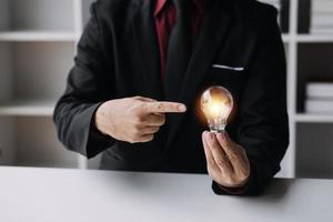 hombre de negocios tocando una bombilla de luz brillante. concepto de ideas para presentar nuevas ideas gran inspiración e innovación nuevo comienzo. foto