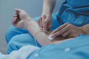 Injured patient showing doctor broken wrist and arm with bandage in hospital office or emergency room. Sprain, stress fracture or repetitive strain injury in hand. Nurse helping customer. First aid. photo