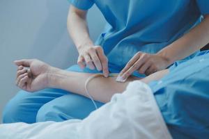 Injured patient showing doctor broken wrist and arm with bandage in hospital office or emergency room. Sprain, stress fracture or repetitive strain injury in hand. Nurse helping customer. First aid. photo