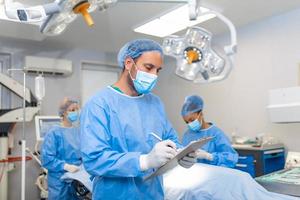 Surgeon writing on clipboard in operation room, anaesthesiologist writing the updates photo