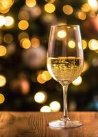 Glass of white wine on a wooden table with bokeh lights background photo