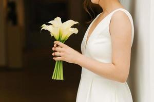 Delicate white bouquet of calla lilies in the hands of the bride at the wedding photo
