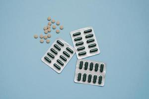 Tablets in capsules and herbal tablets on a blue background photo